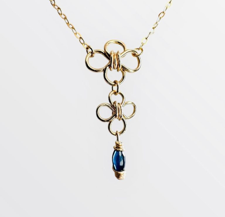 Collier en or avec motifs floraux et une pierre bleue saphir en pendentif. fait main